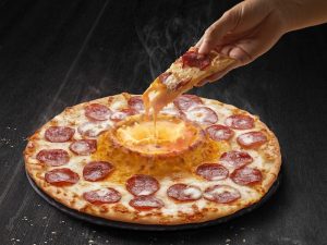 Gambar Cheese Volcano Domino’s dengan keju cair panas di tengah pizza yang lazat